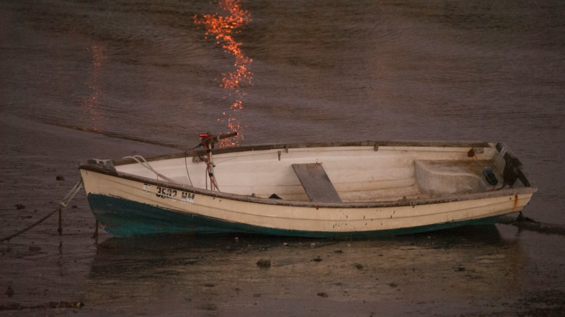 a rowboat on shore, with the reflected sunlight making it look like it's been touched by magic