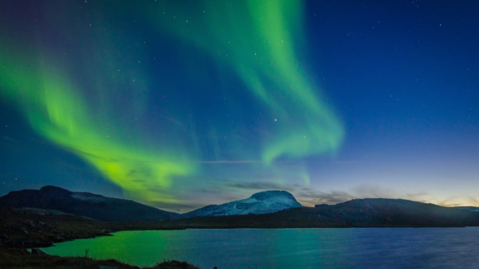 aurora borealis in the north, over a lake and mountains